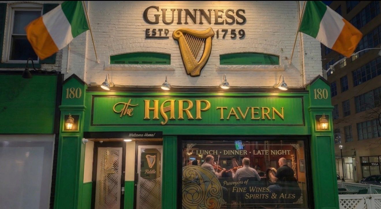 The green and gold frontage of The Harp Tavern at 180 Eglinton Avenue East, with musicians inside